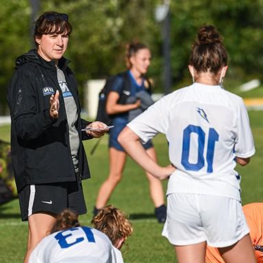 Women's soccer coach speaking with team members during practice